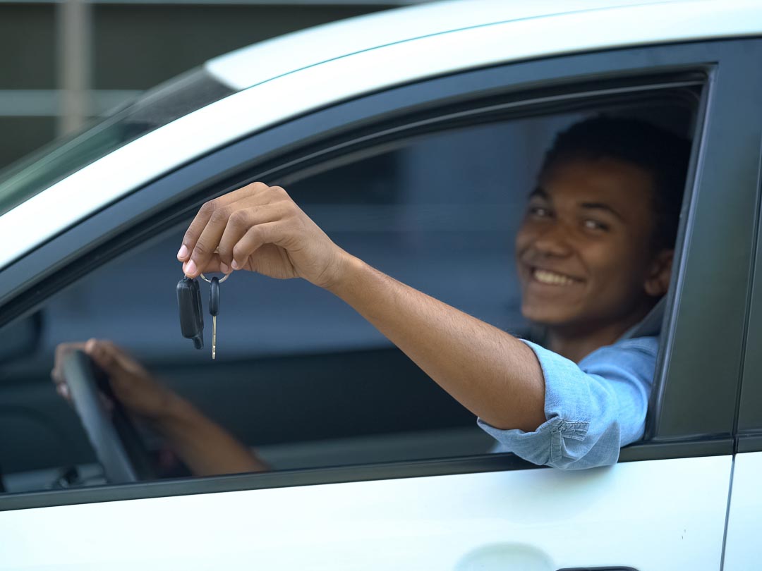 Recent grad of Great Lakes Driving Academy in Sterling Heights, Michigan with driver's license and car keys 